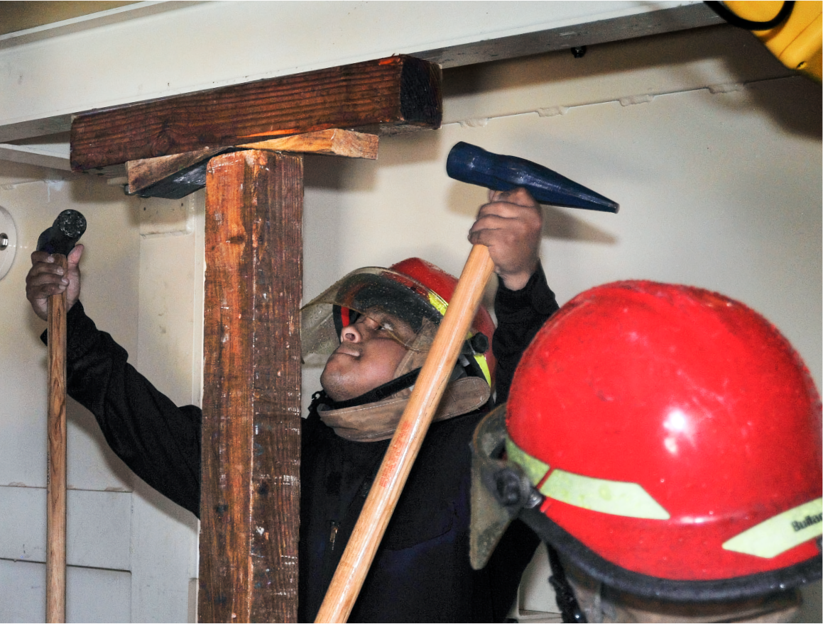Sailors pounding wedges into damage control shoring.